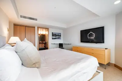 a bedroom with a white bed and a flat screen tv at Le Chamois 508 by Outpost Whistler in Whistler