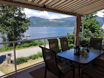 a table and chairs on a porch with a view of a lake at West facing Waterfront Retreat with private beach, dock access & private buoy in Blind Bay