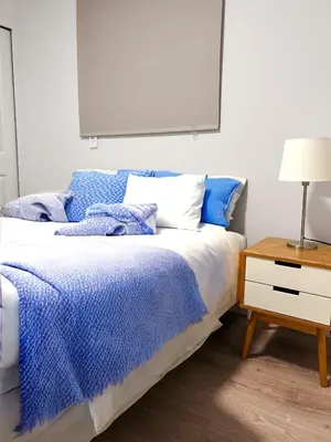 a bedroom with a bed with a blue blanket and a night stand at 1Bd Modern Suite close to Langley Events Centre and Hwy1 in Langley