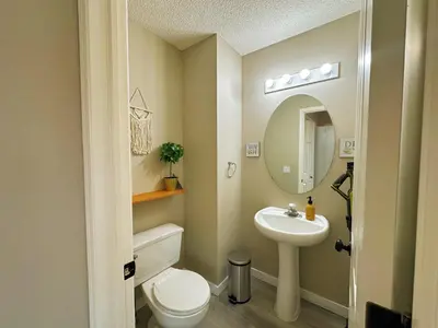 a bathroom with a sink and a toilet and a mirror at Cozy Calgary Hideaway in Calgary