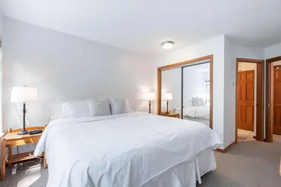 a white bedroom with a large bed and a mirror at Northstar 51 by Outpost Whistler in Whistler