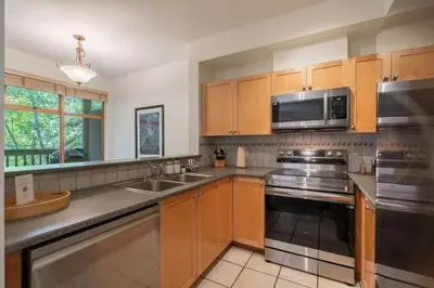 a kitchen with wooden cabinets and stainless steel appliances at Northstar 51 by Outpost Whistler in Whistler