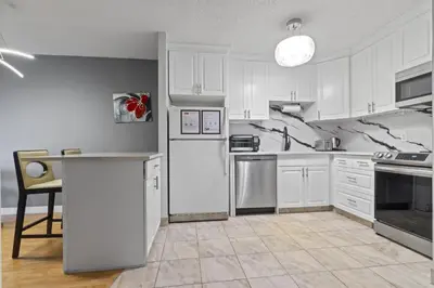 a kitchen with white cabinets and a white refrigerator at Modern 2 bedroom next to Stampede, 17th w Parking in Calgary