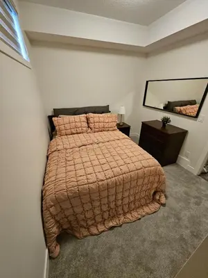 a bedroom with a large bed and a mirror at Emeka & Comfort in Calgary