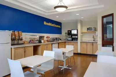 a kitchen with white tables and white chairs and a blue wall at Days Inn by Wyndham Whitecourt in Whitecourt