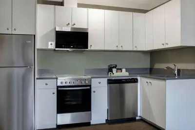 a kitchen with white cabinets and stainless steel appliances at Days Inn by Wyndham Whitecourt in Whitecourt