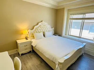 a bedroom with a large white bed with a window at Vancouver Airport Love Home Inn in Richmond