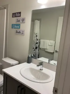 a bathroom with a sink and a mirror at Cozy & Stylish AC Suite Near YYC Airport in Calgary