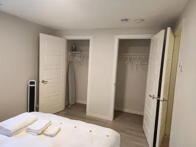a bedroom with a bed and two closets at Cozy & Stylish AC Suite Near YYC Airport in Calgary