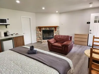 a bedroom with a couch and a chair and a fireplace at Alpenrose 100 King bed Hottub Mountains Views in Golden
