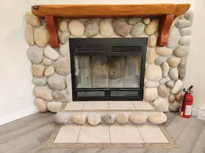 a stone fireplace in a living room with a fire hydrant at Alpenrose 100 King bed Hottub Mountains Views in Golden