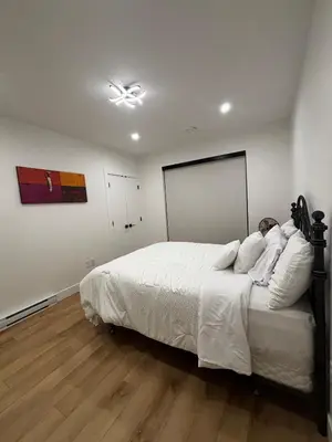 a bedroom with a large bed with white sheets at Hilltop Vistas Kelowna in Kelowna