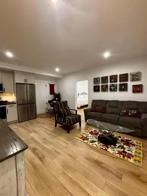 a living room with a couch and a kitchen at Hilltop Vistas Kelowna in Kelowna