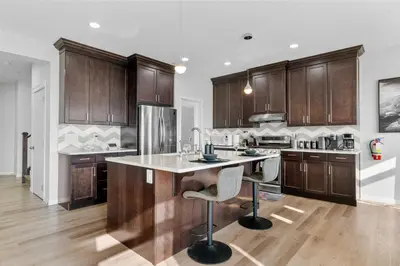 a kitchen with wooden cabinets and a large island at The Ultimate Getaway with Central AC, 3 King Beds, Hot Tub, Pool Table and More in Balzac