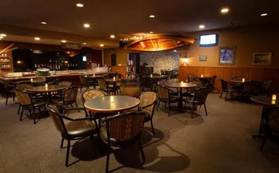 a restaurant with tables and chairs and a bar at Grande Cache Hotel in Grande Cache
