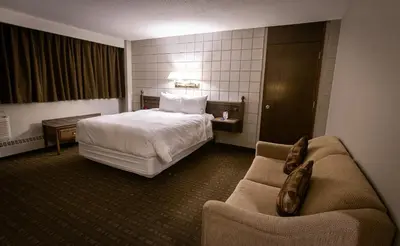 a hotel room with a bed and a couch at Grande Cache Hotel in Grande Cache