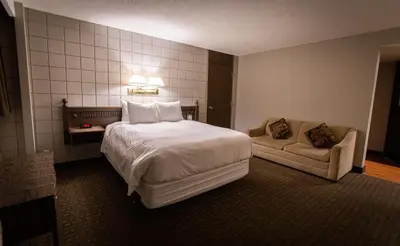a hotel room with a bed and a couch at Grande Cache Hotel in Grande Cache
