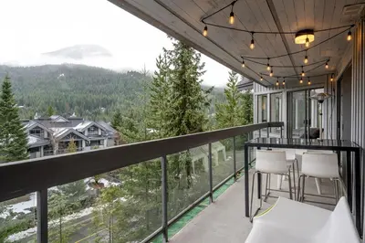 a balcony with a table and chairs and mountains at Ravencrest 204 by Outpost Whistler in Whistler