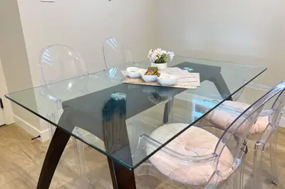 a glass dining room table with chairs and flowers on it at RomanticStylish|FreeWifi|KingBed|WEM|parking in Edmonton