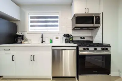 a white kitchen with a stove and a microwave at •SteamyRomanticBsmntSuite•KingBed•Wifi•Netflix in Edmonton