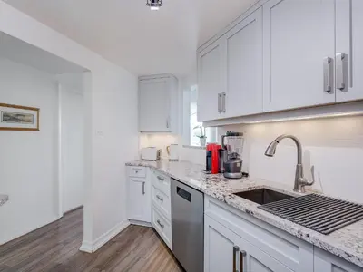 a kitchen with white cabinets and a sink at Coastal Duet - min 3-Day Stay Breathtaking Views with Work Desk by Victoria Prime! in Victoria