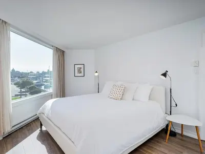 a bedroom with a large white bed and a large window at Coastal Duet - min 3-Day Stay Breathtaking Views with Work Desk by Victoria Prime! in Victoria