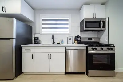 a kitchen with white cabinets and stainless steel appliances at RoyalBlueBSMTsuite/KingBed/FreeParking/Netflix in Edmonton