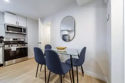 a dining room with a glass table and blue chairs at ~SweetTropicalBSMTsuite~KingBed|WIFI•parking in Edmonton