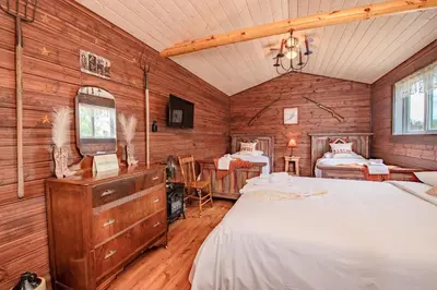 a bedroom with two beds in a room with wooden walls at Prairie Junction Rustic Cabins Stettler in Stettler