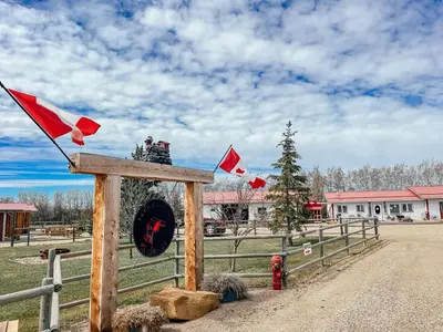 a wooden sign with flags on a fence at Prairie Junction Rustic Cabins Stettler in Stettler