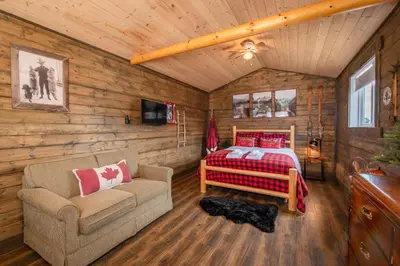 a bedroom with a bed and a couch in a room at Prairie Junction Rustic Cabins Stettler in Stettler