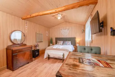 a bedroom with a bed and a mirror and a table at Prairie Junction Rustic Cabins Stettler in Stettler