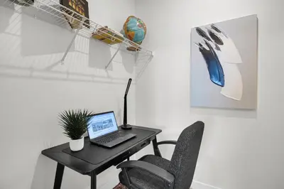 a desk with a laptop and a chair in a room at New Luxury Sleeps 7 AC Double Garage in Edmonton