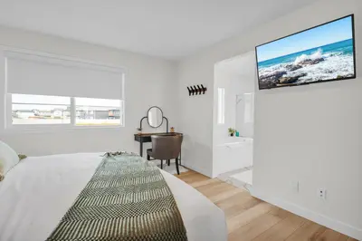 a white bedroom with a large bed and a desk at Trendy & Spacious Sleeps 9 AC Db Garage in Edmonton