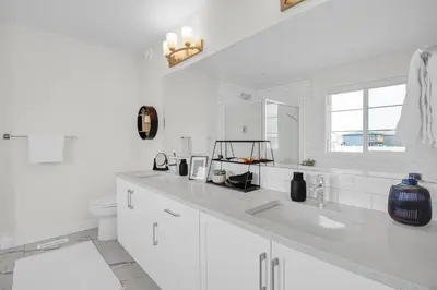 a white bathroom with a sink and a toilet at Trendy & Spacious Sleeps 9 AC Db Garage in Edmonton