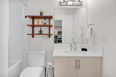 a white bathroom with a toilet and a sink at Trendy & Spacious Sleeps 9 AC Db Garage in Edmonton