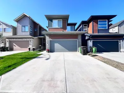 a house with two garage doors in a driveway at Trendy & Spacious Sleeps 9 AC Db Garage in Edmonton