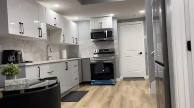 a kitchen with white cabinets and a stove top oven at Blissful Nest - Cozy, Classy 2 Bedroom Private Suite Netflix, free Parking, 20 minutes to West Edmonton Mall and Airport in Edmonton