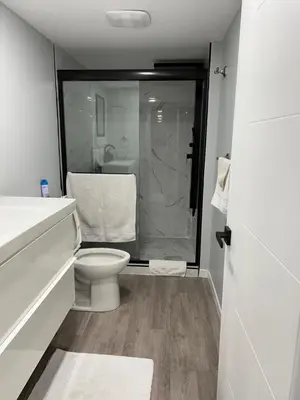 a white bathroom with a toilet and a shower at Gorgeous Basement Apartment in Calgary