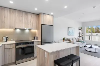 a kitchen with wooden cabinets and a living room at Modern North Shore Nest with Balcony in North Vancouver