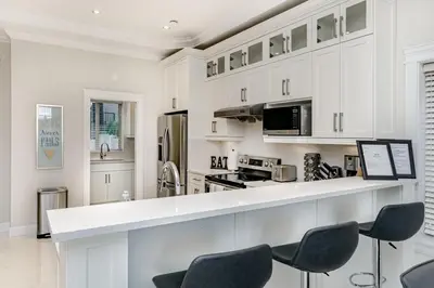 a kitchen with white cabinets and a counter with chairs at Upscale 4BR Vancouver in Vancouver