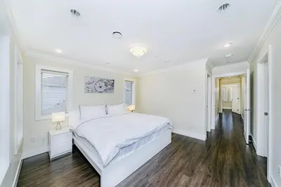 a white bedroom with a large white bed and wooden floors at Upscale 4BR Vancouver in Vancouver