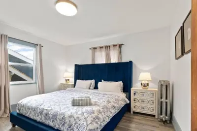 a bedroom with a blue bed and a window at Charming 2 bedroom Duplex steps from Jericho Beach in Vancouver