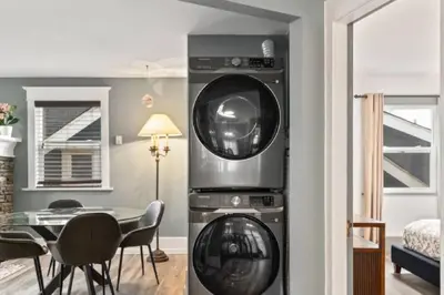 a washing machine in a living room with a table at Charming 2 bedroom Duplex steps from Jericho Beach in Vancouver