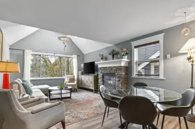 a living room with a table and a fireplace at Charming 2 bedroom Duplex steps from Jericho Beach in Vancouver