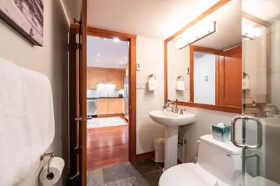 a bathroom with a sink and a toilet and a mirror at Ravencrest 309 by Outpost Whistler in Whistler