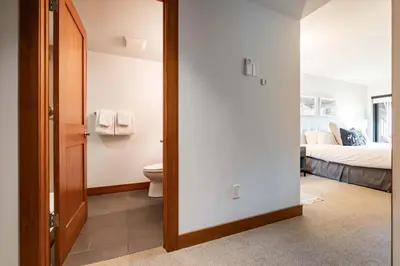 a bathroom with a toilet and a bedroom with a bed at Ravencrest 309 by Outpost Whistler in Whistler