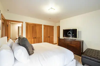 a bedroom with a white bed and a flat screen tv at Taluswood 14 by Outpost Whistler in Whistler