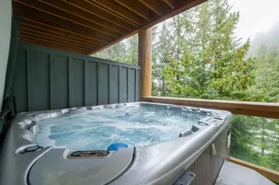 a jacuzzi tub on a deck with a window at Taluswood 14 by Outpost Whistler in Whistler