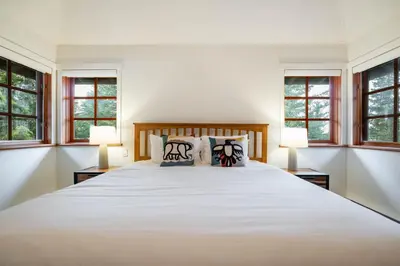 a bedroom with a large white bed with windows at Taluswood 36 by Outpost Whistler in Whistler